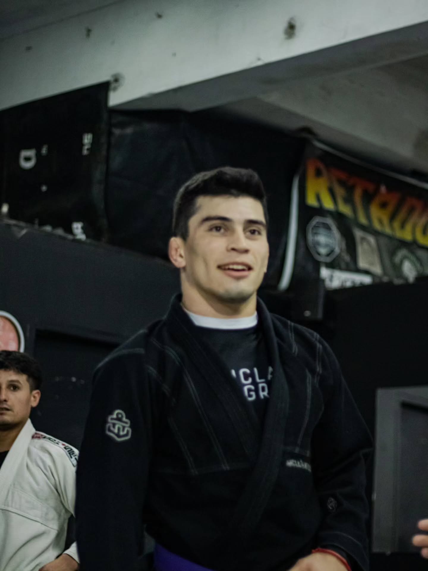 Chino Vallejos sonriendo con kimono negro y cinturón violeta en su academia