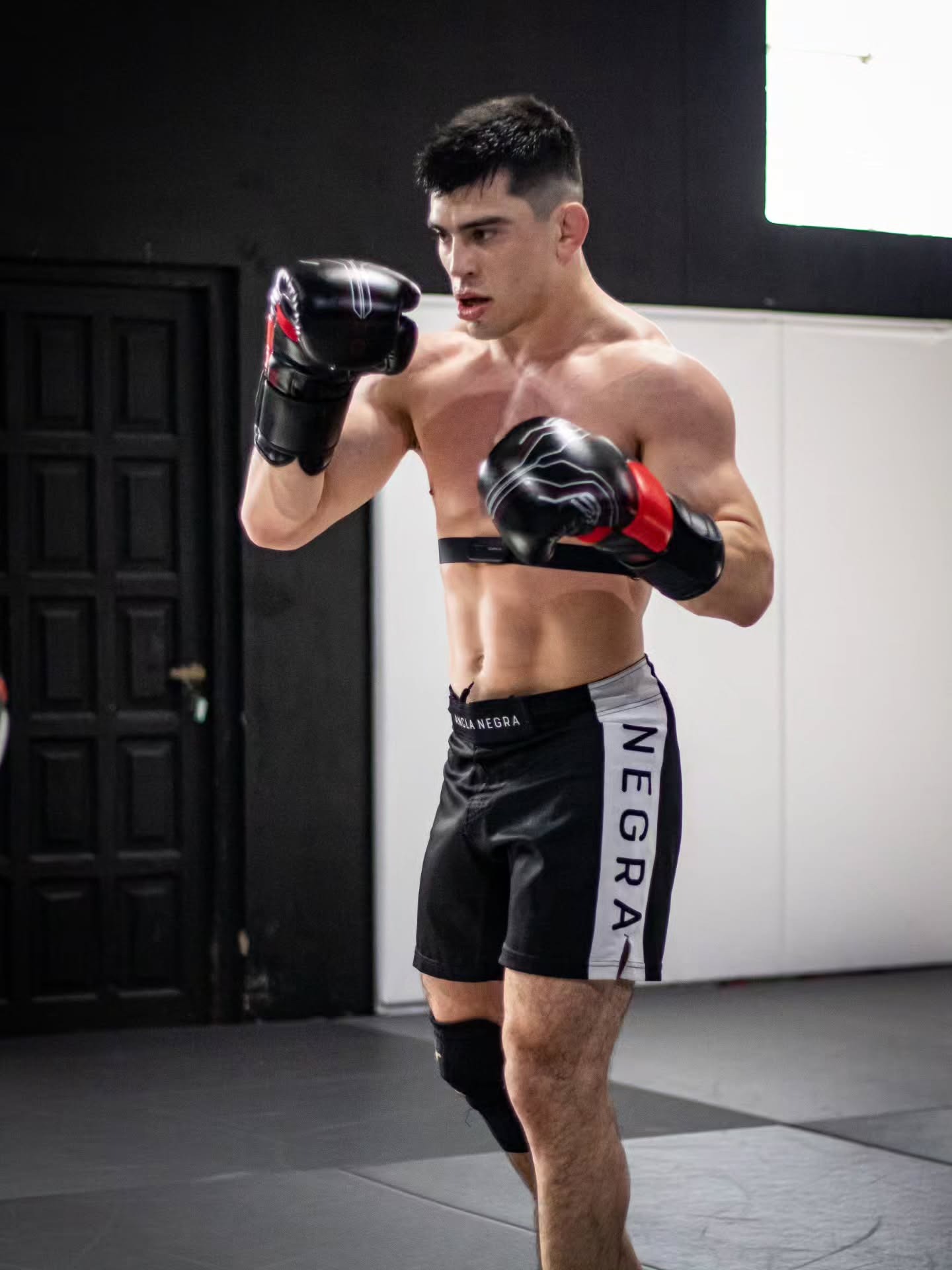 Chino Vallejos en guardia con guantes de boxeo y short Ancla Negra