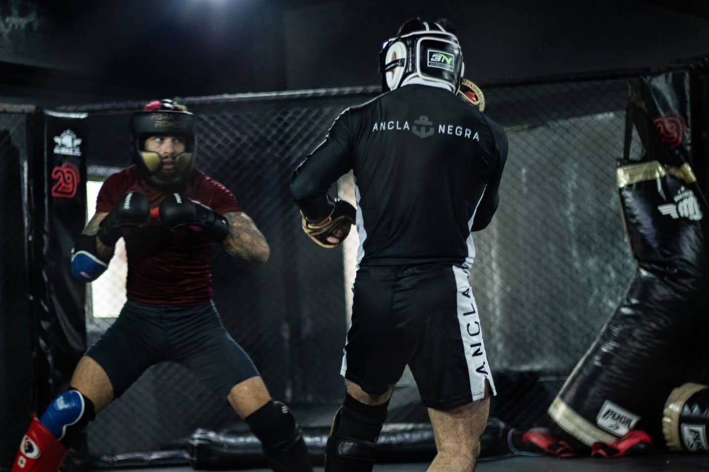 Chino Vallejos de espaldas entrenando en la jaula, con ANCLA NEGRA en la campera
