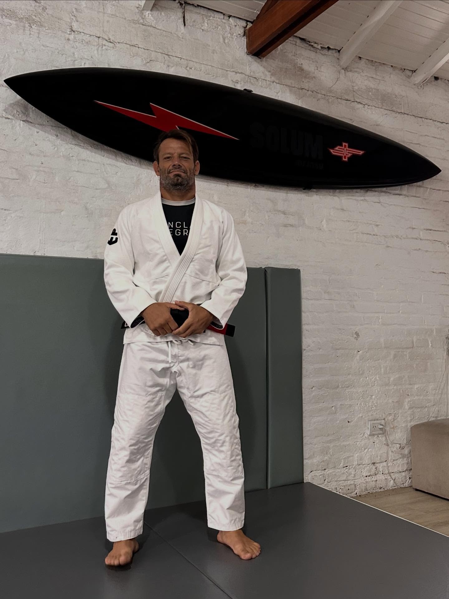 Martín Passeri con kimono blanco frente a una tabla de surf colgada en la pared