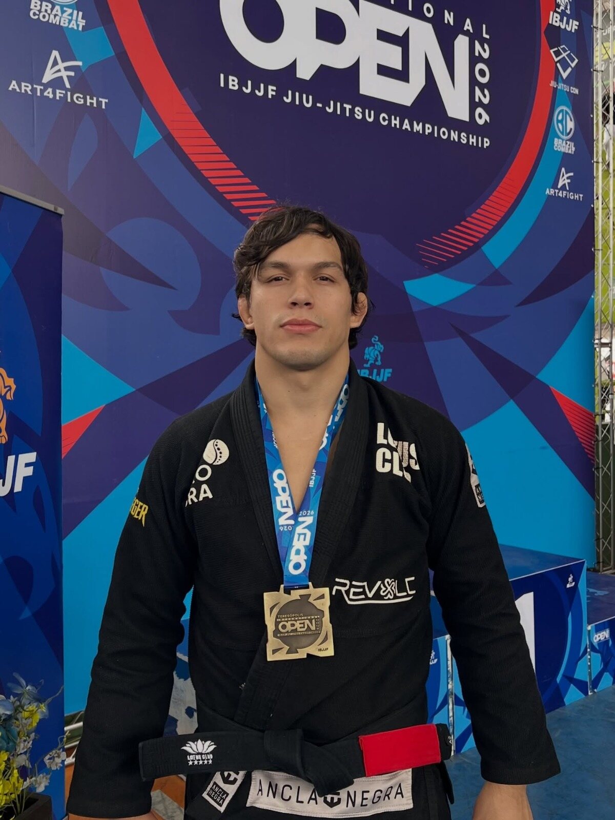 Mateo Ruiz con kimono negro y una medalla de oro al cuello, frente al panel de un campeonato